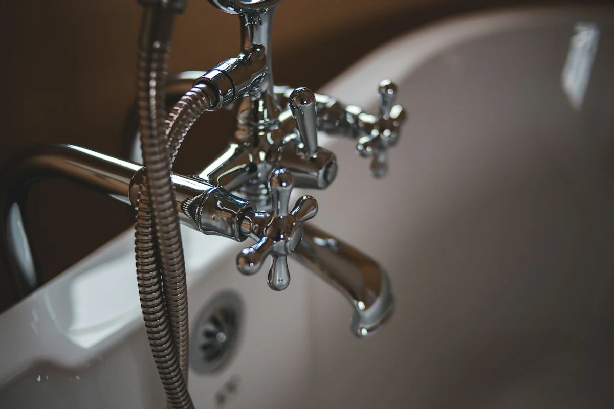 Polished chrome vintage faucet with cross handles and braided supply lines on white sink